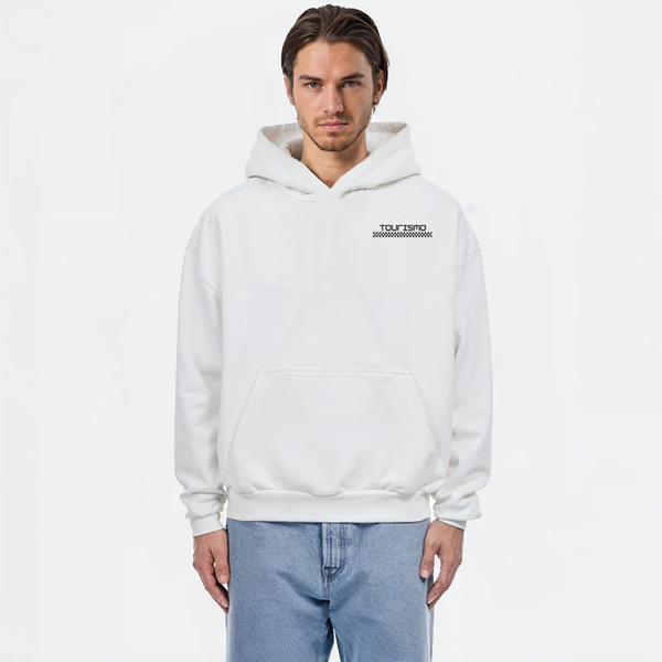 Sweat à capuche blanc avec logo noir "TOURISMO", porté par un homme en jean clair sur fond blanc lumineux