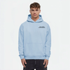 Homme portant un hoodie bleu ciel TOURISMO avec pantalon foncé, fond blanc