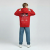 Enfant vu de dos en sweat rouge Charles Leclerc, visuel paddock noir avec typographie LECLERC, posture droite, capuche baissée, fond neutre.
