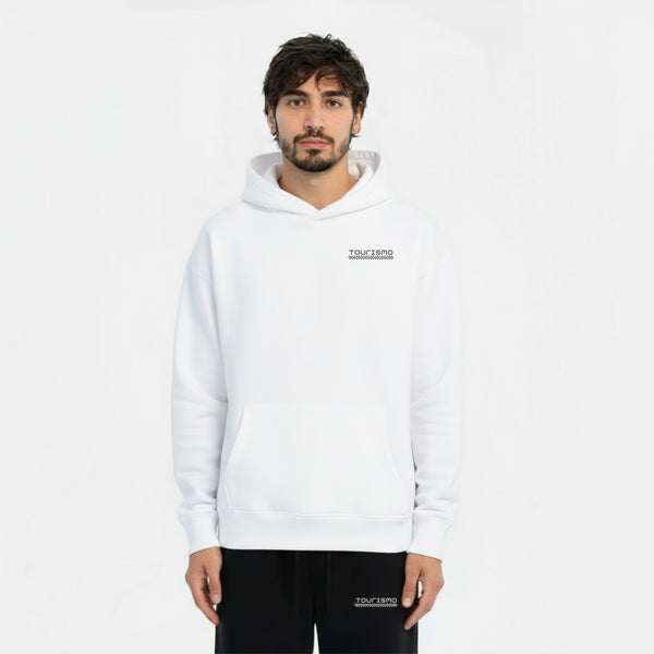 Homme portant un hoodie blanc TOURISMO avec un pantalon noir, regardant l’objectif