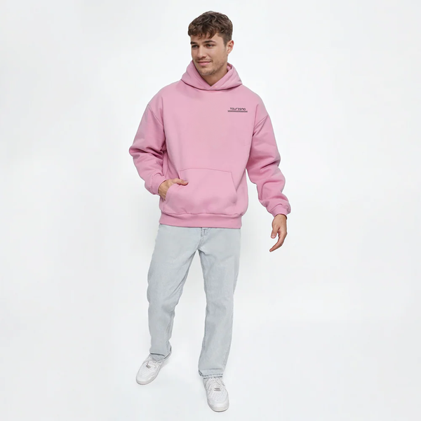 Homme portant un hoodie rose TOURISMO avec un jean clair, look casual et moderne