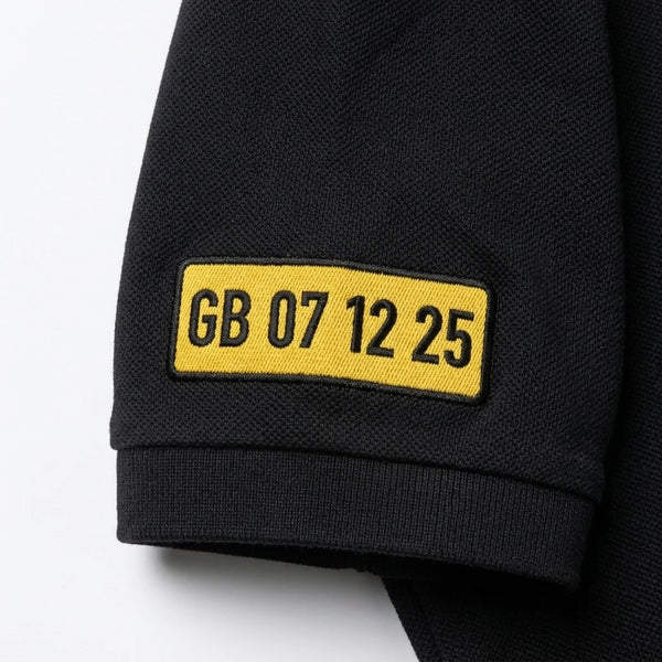 Nahaufnahme des am Ärmel gestickten Kennzeichens GB 07 12 25 auf dem Polo in Schwarz