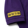 Nahaufnahme des am Ärmel gestickten Kennzeichens GB 02 11 08 auf dem Polo in Violett