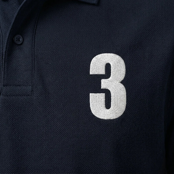 Nahaufnahme der weiß gestickten 3 auf dem Max Verstappen Polo in Marineblau
