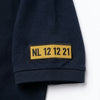 Nahaufnahme des am Ärmel gestickten Kennzeichens NL 12 12 21 auf dem Polo in Marineblau