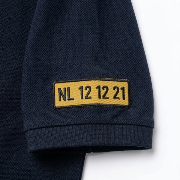 Nahaufnahme des am Ärmel gestickten Kennzeichens NL 12 12 21 auf dem Polo in Marineblau