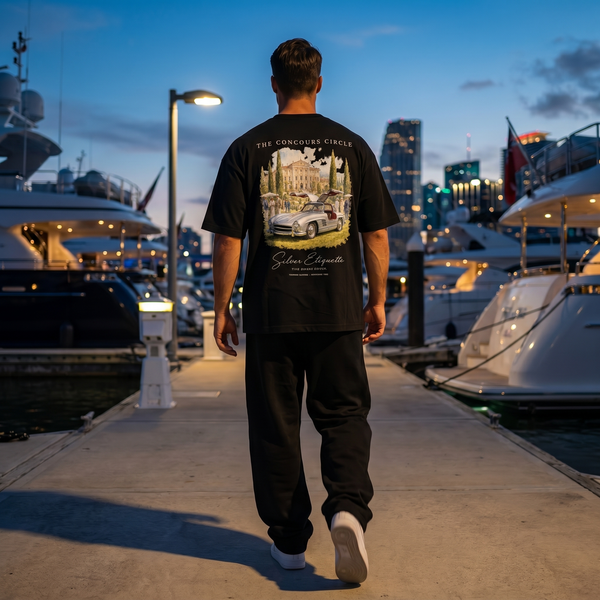 Homme portant le t-shirt noir Concours Circle 300 SL sur un quai de marina au crépuscule