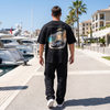 Homme portant le t-shirt noir Riviera Overboost McLaren P1 sur une promenade de port méditerranéen